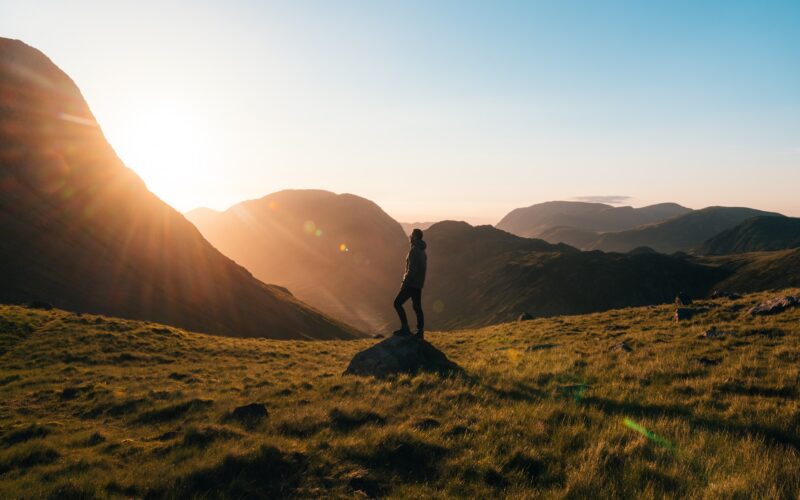 /silhouette-photography-of-person-standing-on-green-grass